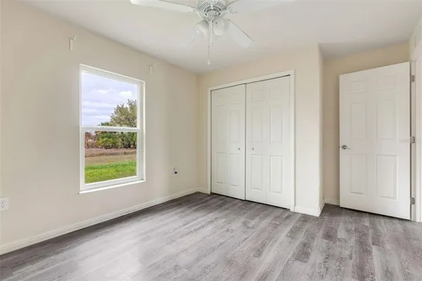 a view of an empty room with a window and wooden floor