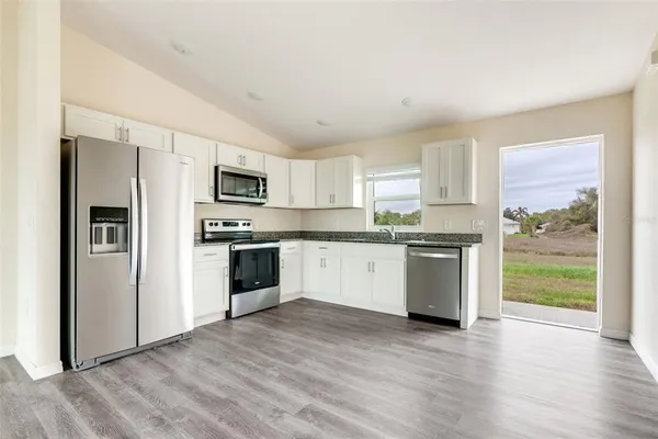 a kitchen with a refrigerator a stove top oven and wooden floor