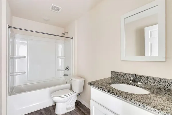 a bathroom with a granite countertop sink toilet mirror and shower