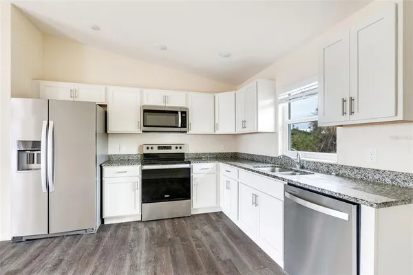 a kitchen with granite countertop white cabinets and stainless steel appliances
