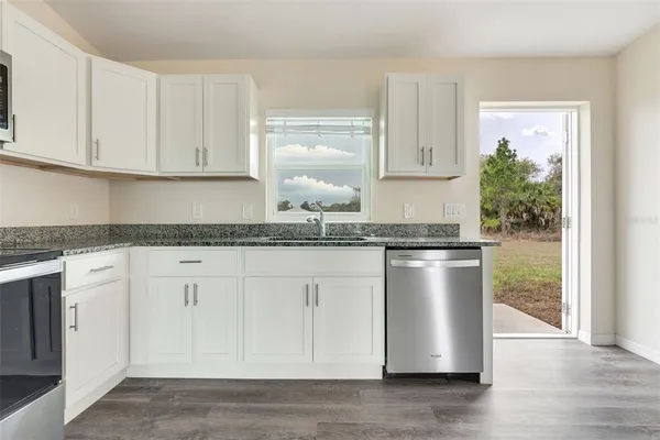 a kitchen with granite countertop white cabinets and white appliances