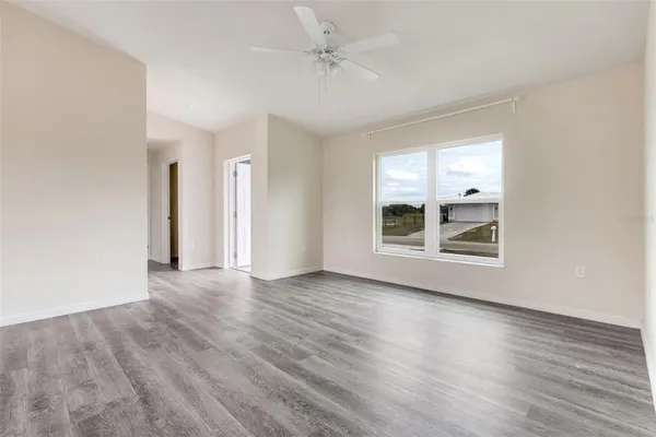 an empty room with wooden floor cabinet and windows