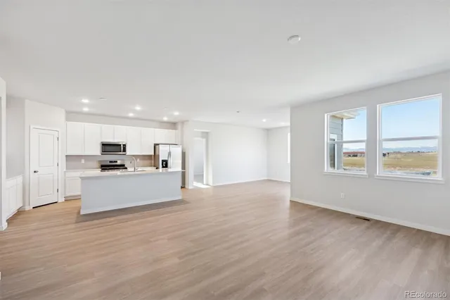 a view of kitchen with kitchen island a sink wooden floor and a stove