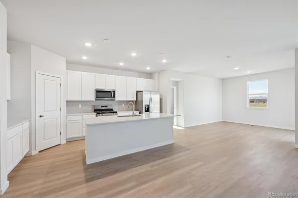 a view of kitchen with stainless steel appliances refrigerator stove microwave and cabinets