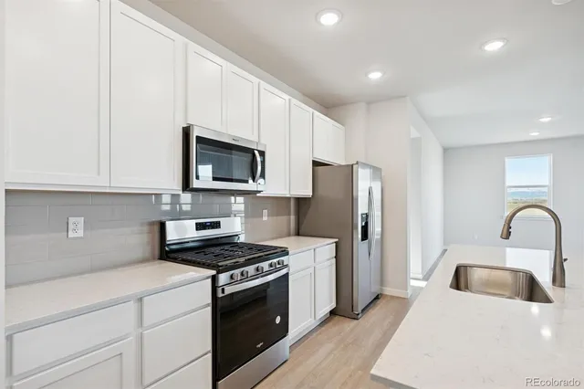 a kitchen with granite countertop a refrigerator stove and microwave