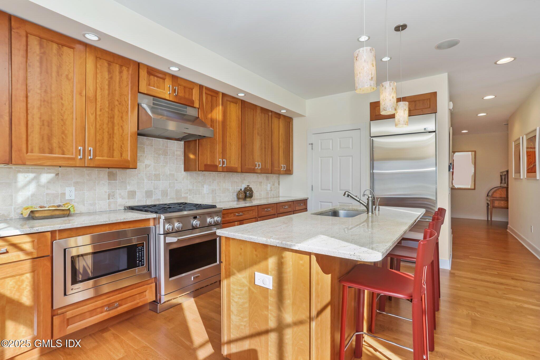 77 Havemeyer Lane, Unit 426 Stamford, CT 06902 - Photo 8 of 23 a kitchen with stainless steel appliances granite countertop a stove a sink dishwasher and a refrigerator with wooden floor