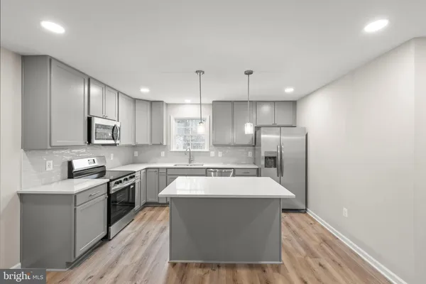a large kitchen with a large counter top stainless steel appliances and cabinets