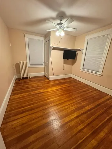a view of an empty room with wooden floor and cabinet