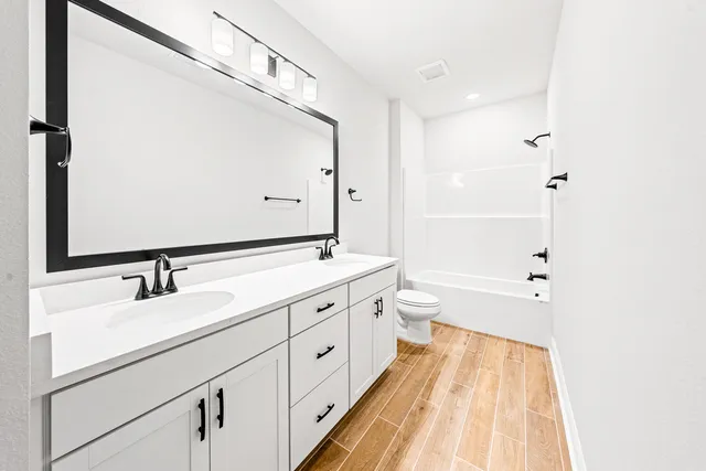 a spacious bathroom with a double vanity sink a mirror and a bathtub