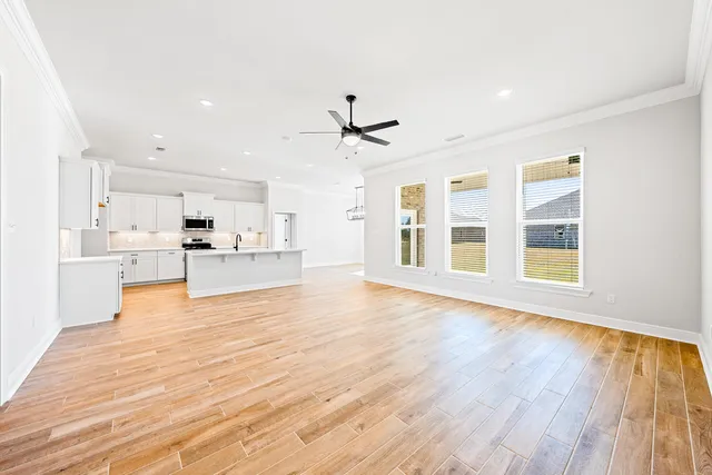 a view of a kitchen with kitchen island wooden floors appliances and a window
