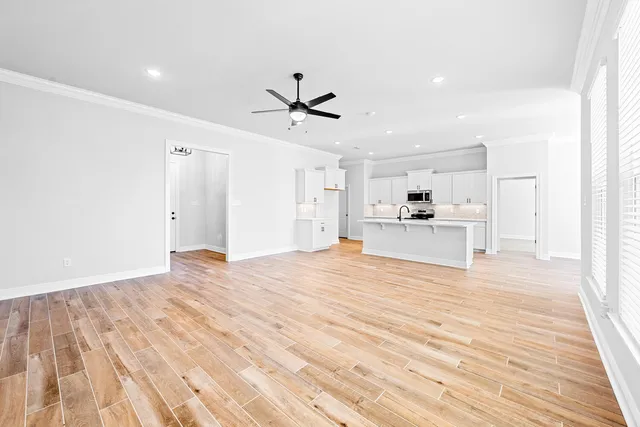 a big room with wooden floor and kitchen view