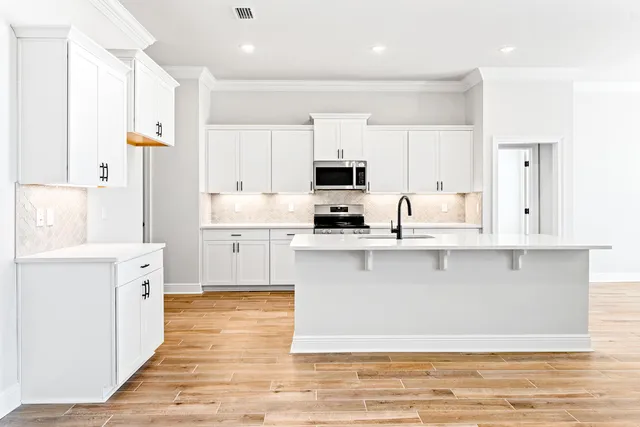 a large kitchen with stainless steel appliances cabinets a sink and a stove