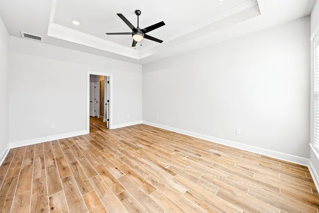 an empty room with wooden floor and a ceiling fan