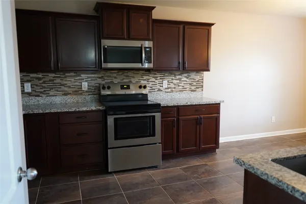 a kitchen with granite countertop a stove and a microwave