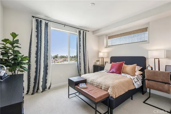 a bedroom with a bed table and a potted plant