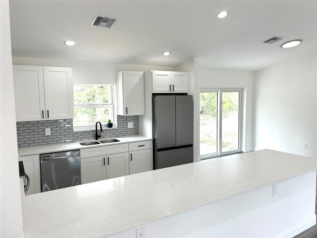 136 Lincoln Road Northwest Lake Placid, FL 33852 - Photo 11 of 31 a kitchen with stainless steel appliances granite countertop a refrigerator a sink dishwasher a stove and white countertops with wooden floor