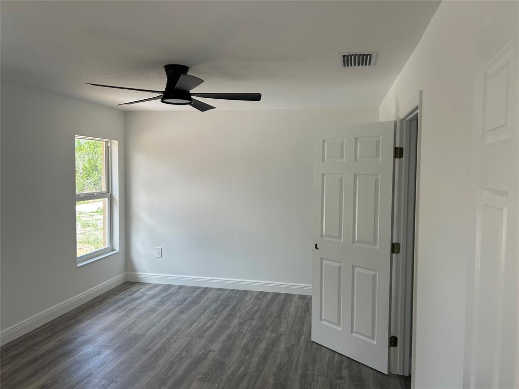136 Lincoln Road Northwest Lake Placid, FL 33852 - Photo 27 of 31 an empty room with wooden floor ceiling fan and windows