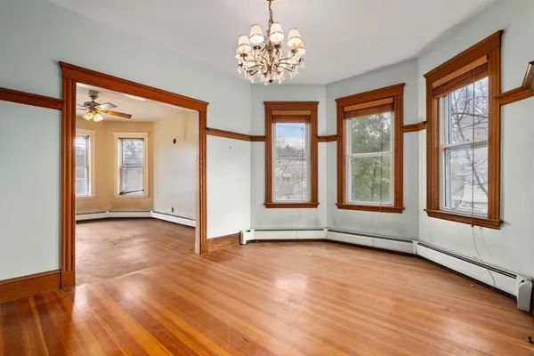a view of an empty room with a window and wooden floor