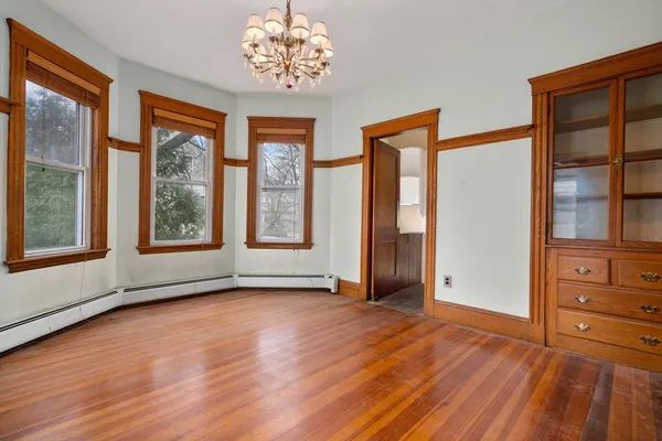 a view of an empty room with a window and wooden floor