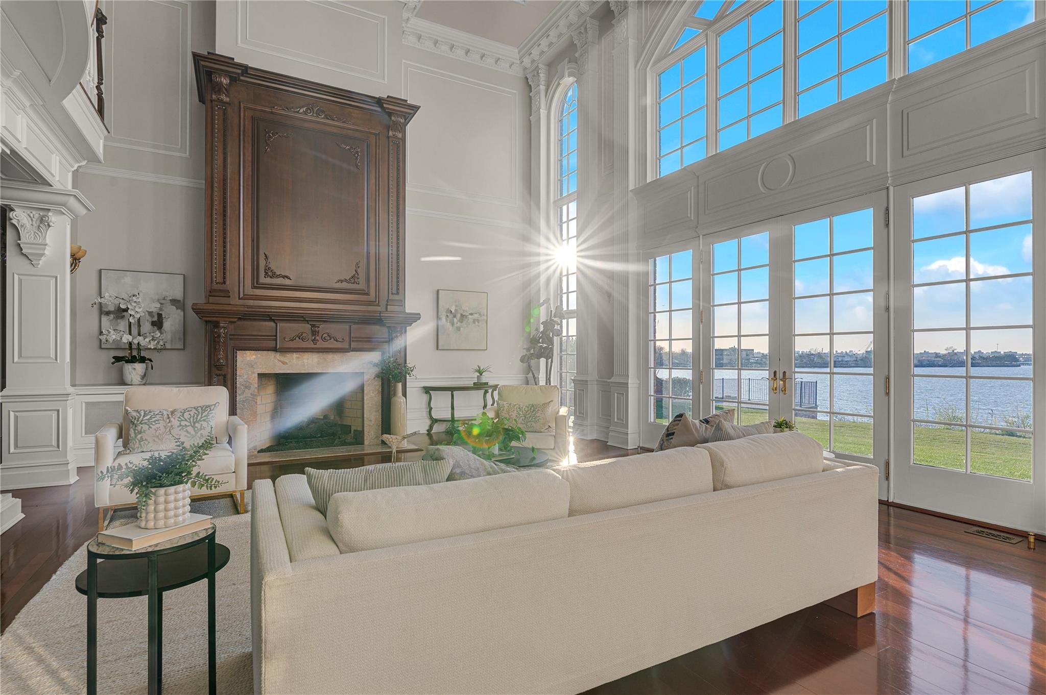 3 Point Crescent Queens, NY 11357 - Photo 12 of 38 Living area with a decorative wall, a fireplace, a towering ceiling, a water view, and dark wood finished floors