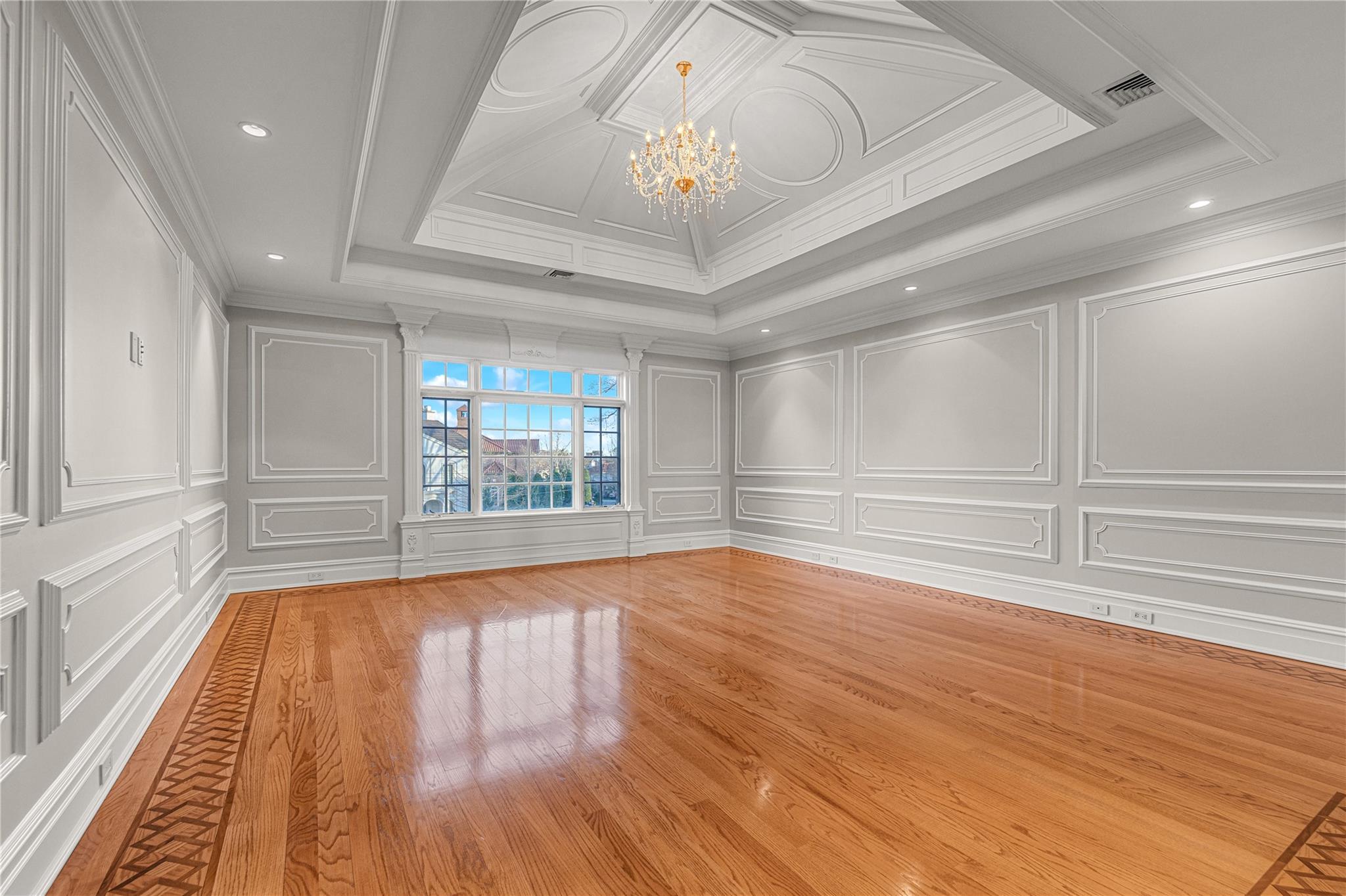 3 Point Crescent Queens, NY 11357 - Photo 21 of 38 Empty room featuring a decorative wall, a chandelier, ornamental molding, wood finished floors, and a tray ceiling