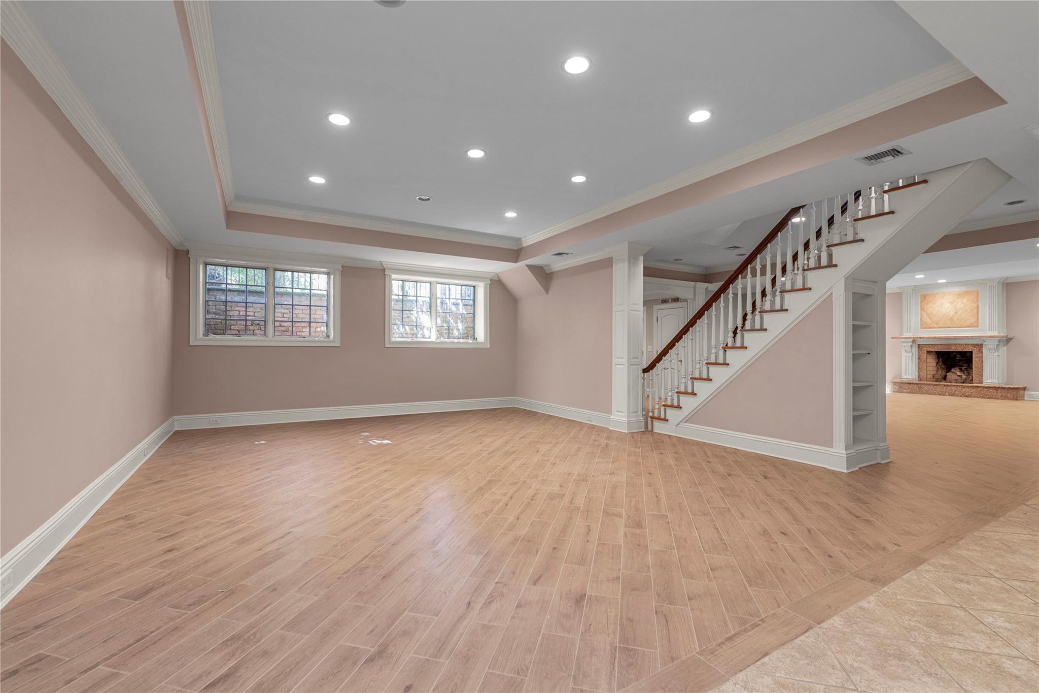 3 Point Crescent Queens, NY 11357 - Photo 29 of 38 Unfurnished living room featuring ornamental molding, a raised ceiling, stairway, recessed lighting, and baseboards