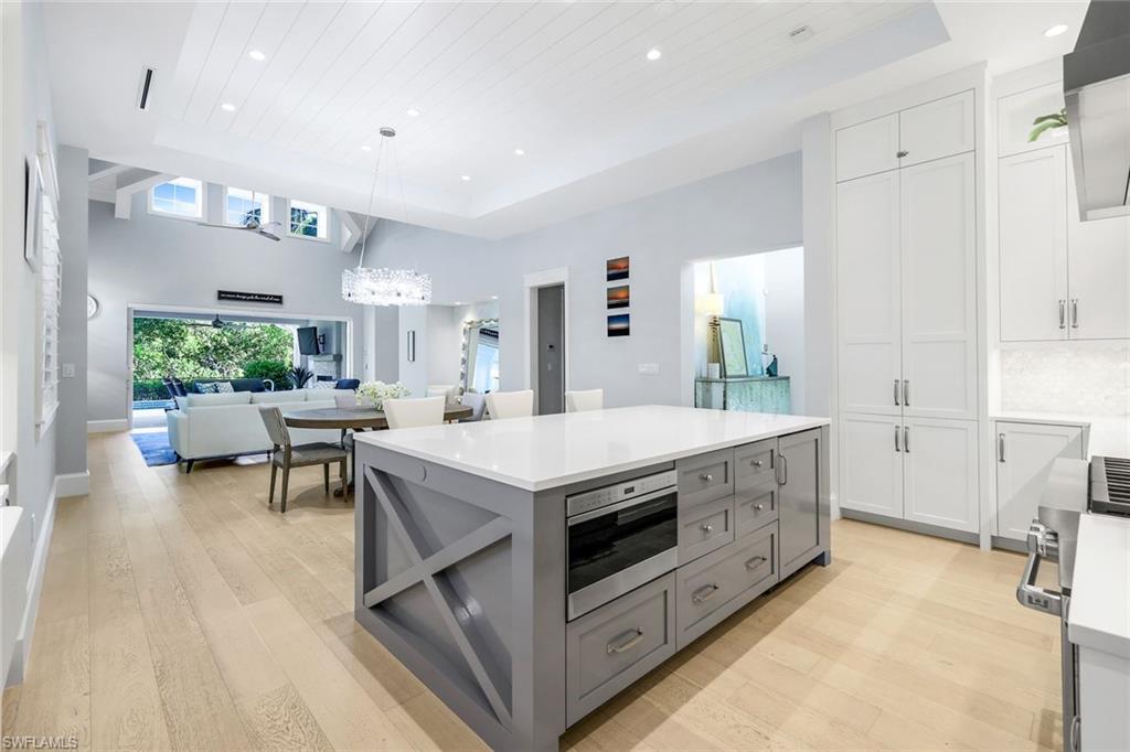 1463 2nd Avenue South Naples, FL 34102 - Photo 10 of 43 a kitchen with kitchen island a stove a sink a dining table and chairs