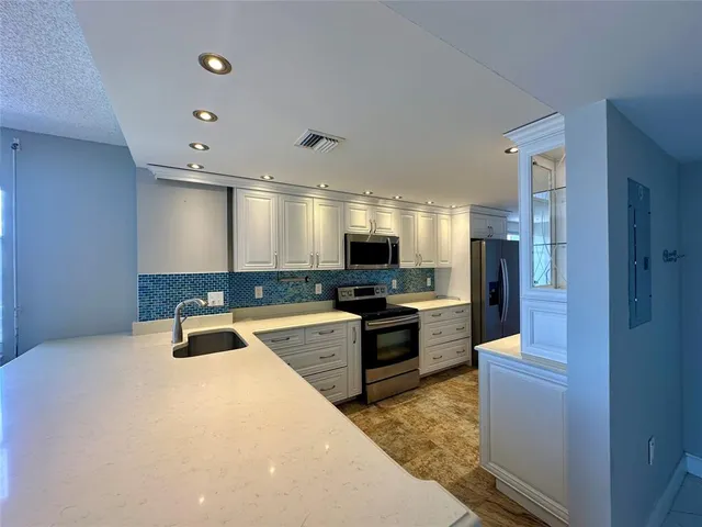 a large kitchen with kitchen island a sink stainless steel appliances and a counter top space