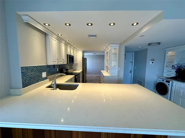 a kitchen with granite countertop white cabinets and stainless steel appliances