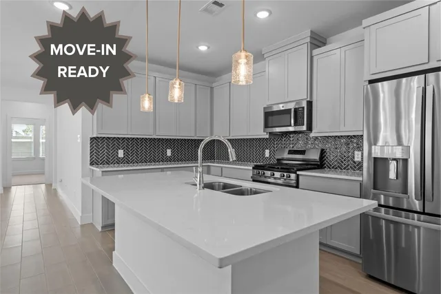 a kitchen with stainless steel appliances a sink a stove a microwave a sink a refrigerator and chairs