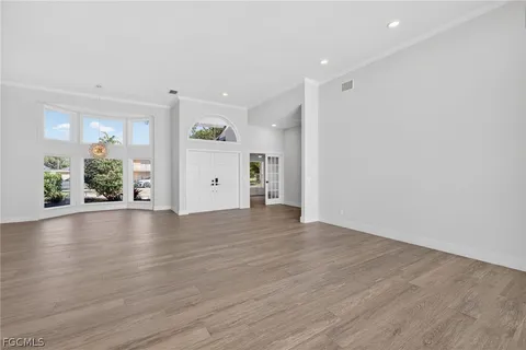 a view of an empty room with wooden floor ceiling fan