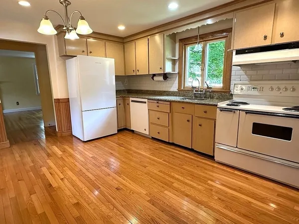 a kitchen with a refrigerator a stove a sink and dishwasher with wooden floor