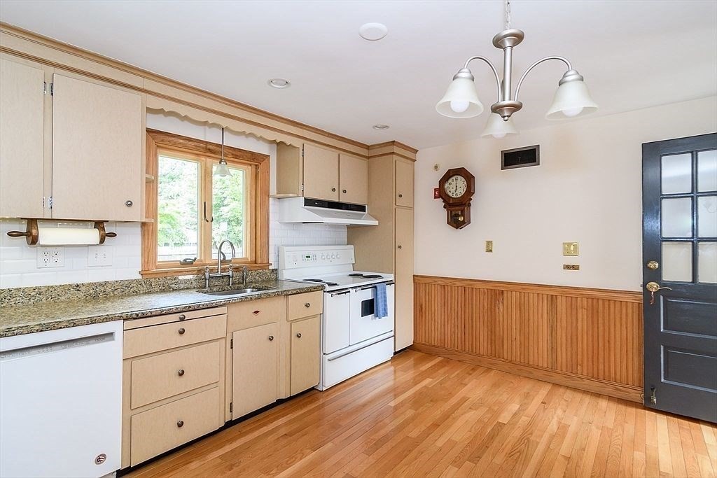 115 Parker Road Wellesley, MA 02482 - Photo 6 of 21 a kitchen with granite countertop a stove a sink dishwasher and white cabinets with wooden floor
