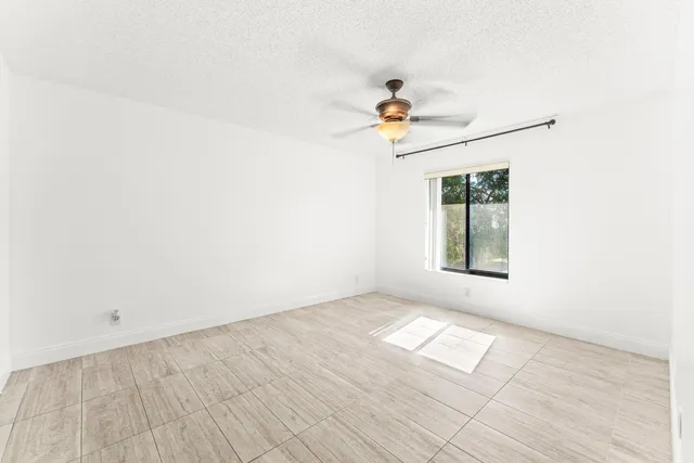 an empty room with a window and ceiling fan