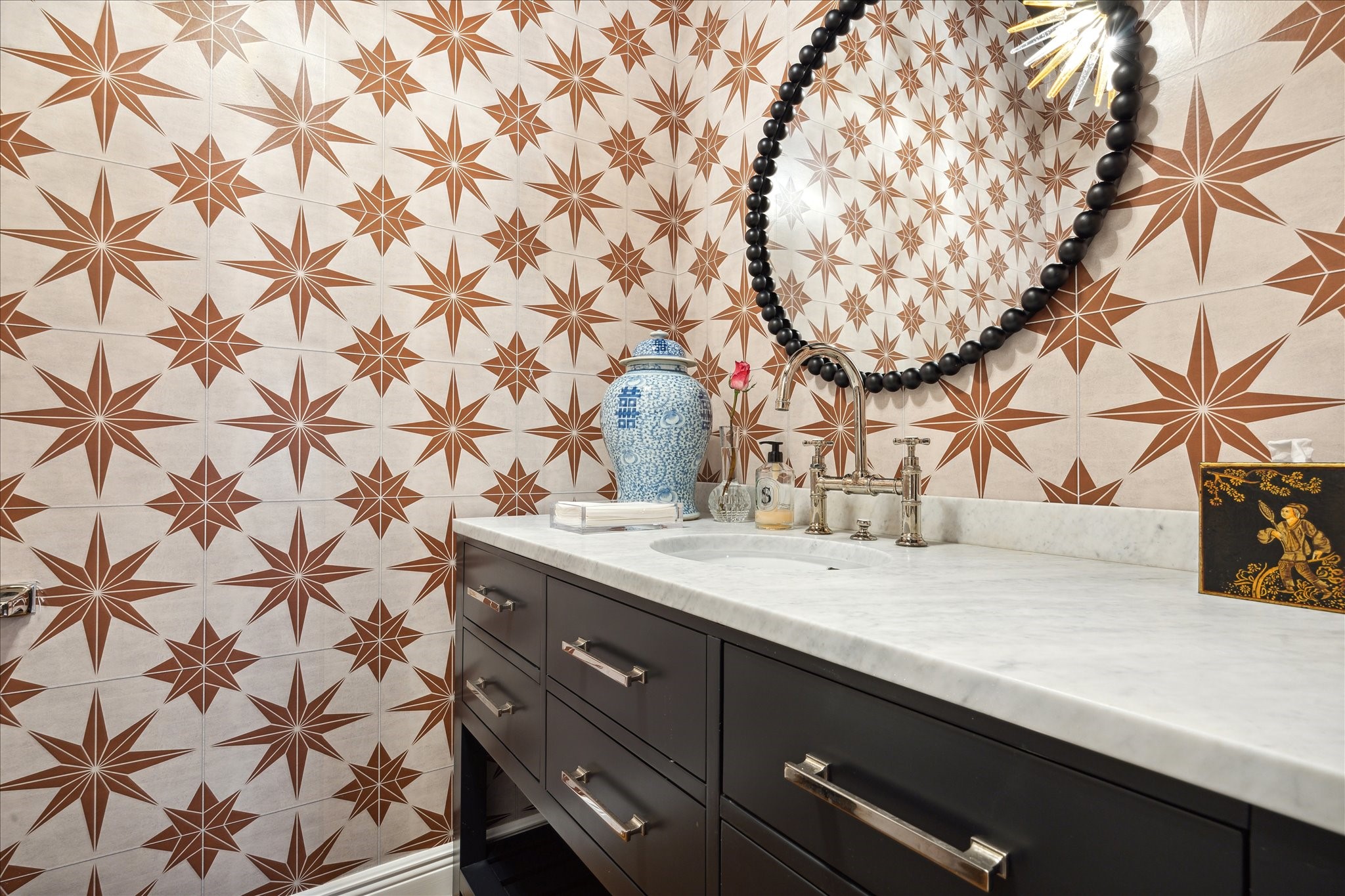 606 Rutland Street Houston, TX 77007 - Photo 30 of 48 This powder room on the first floor features bold star-patterned wallpaper, a sleek marble countertop, and modern dark cabinetry.