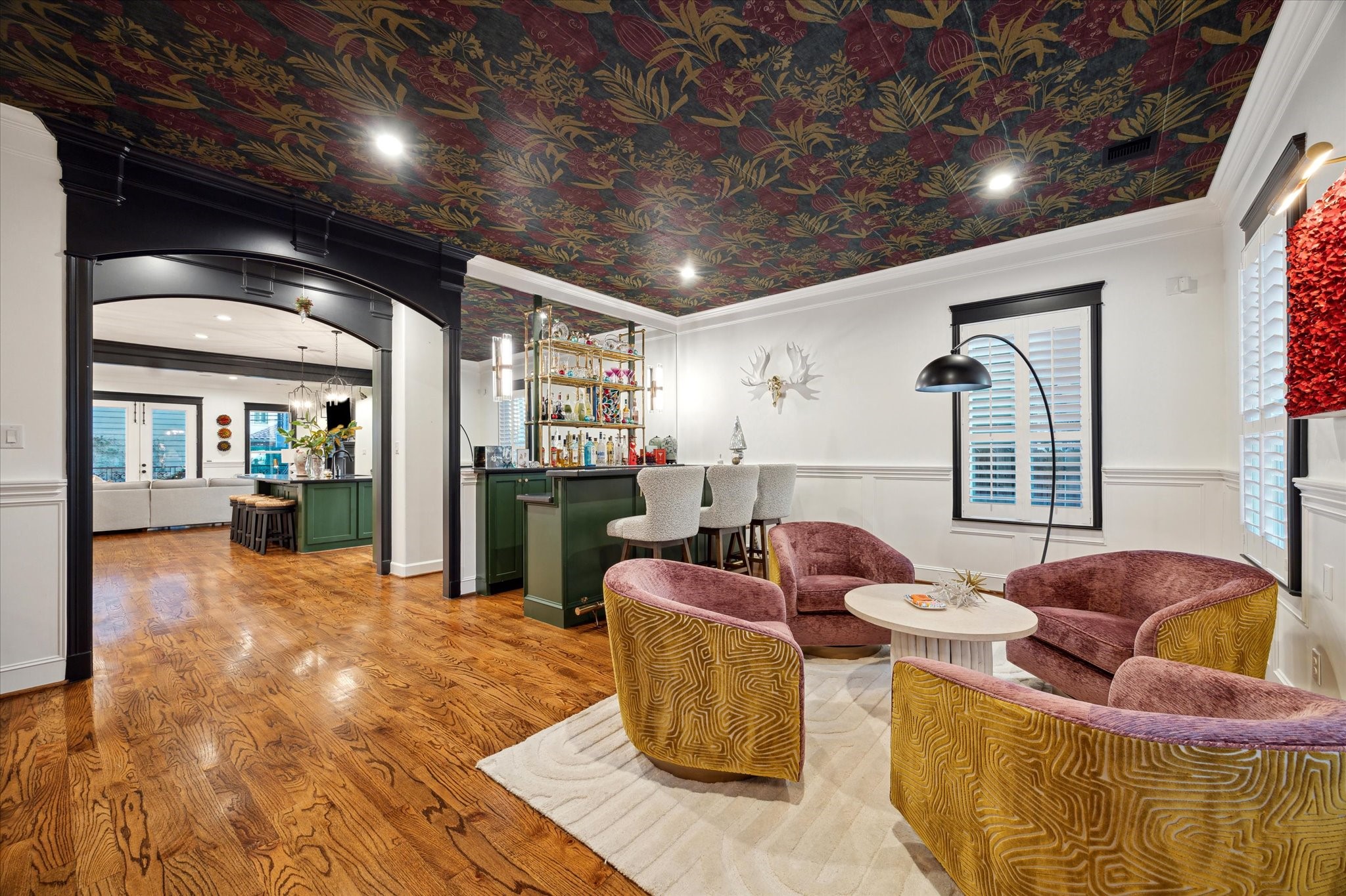 606 Rutland Street Houston, TX 77007 - Photo 8 of 48 This vibrant living area features a stylish bar with green cabinetry, brass shelving and bold patterned ceilings creating a welcoming atmosphere, perfect for entertaining. The open design seamlessly connects to rest of the first floor living spaces