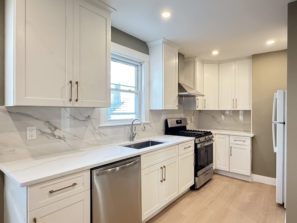 a kitchen with stainless steel appliances granite countertop a sink stove and refrigerator