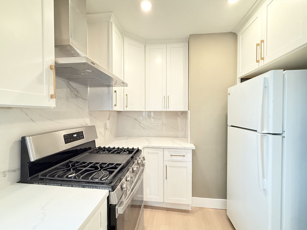 21 High Street, Unit 1 Somerville, MA 02144 - Photo 2 of 14 a kitchen with a refrigerator a stove a microwave and cabinets