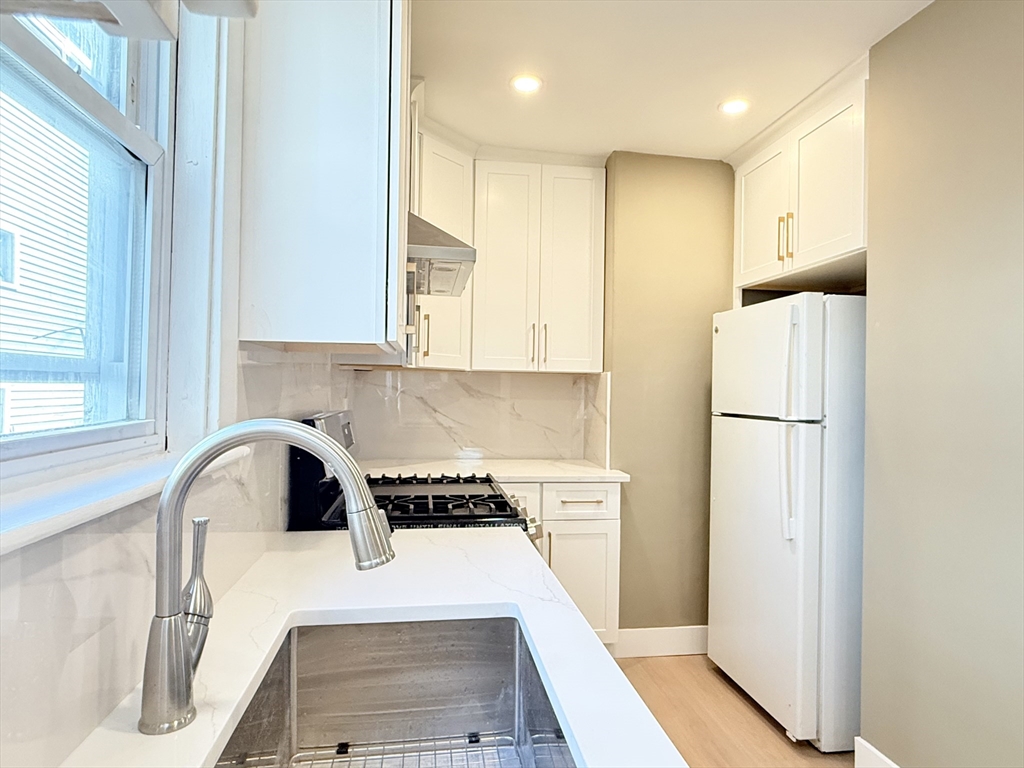 21 High Street, Unit 1 Somerville, MA 02144 - Photo 3 of 14 a kitchen with a refrigerator a sink and a stove top oven