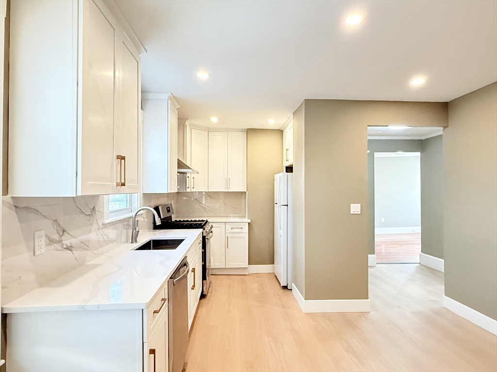 21 High Street, Unit 1 Somerville, MA 02144 - Photo 5 of 14 a kitchen with a sink a refrigerator and cabinets