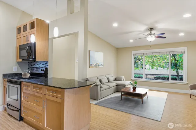 a kitchen with granite countertop a stove and white cabinets with wooden floor