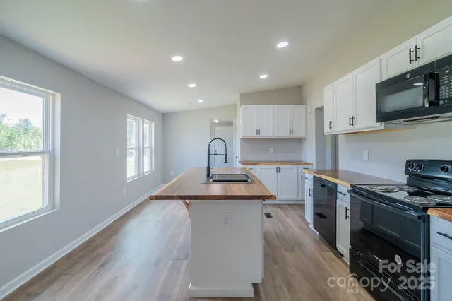 a kitchen with stainless steel appliances granite countertop a stove top oven a sink dishwasher and a refrigerator with wooden floor