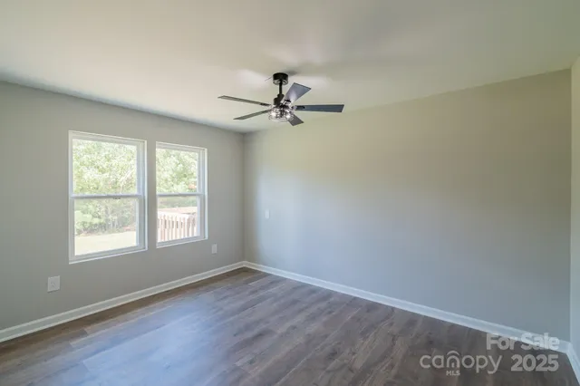 wooden floor in an empty room with a chandelier fan