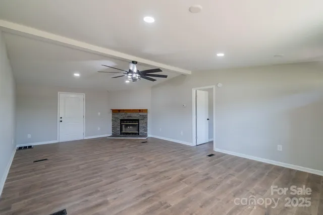 an empty room with wooden floor fan and windows