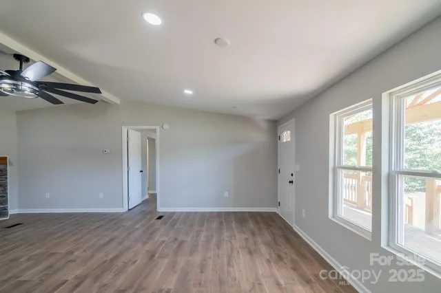 an empty room with wooden floor fireplace and windows
