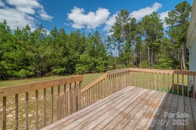 a balcony with wooden floor and trees in the background