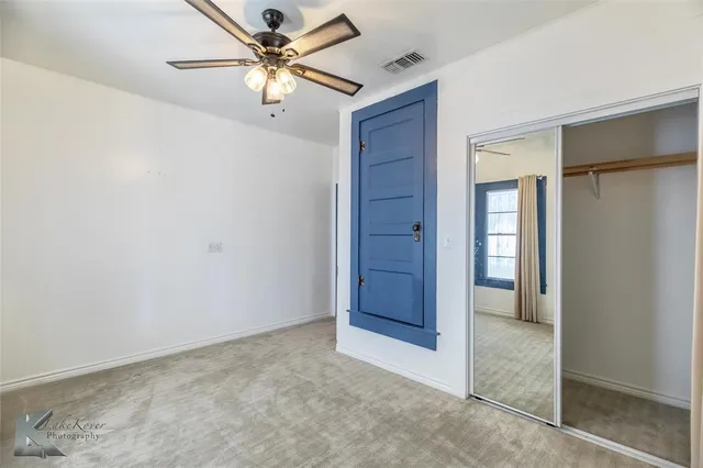 an empty room with closet and a ceiling fan