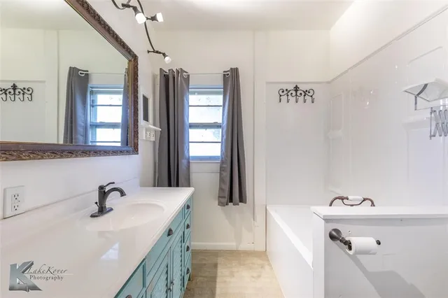 a bathroom with a sink a tub and a mirror