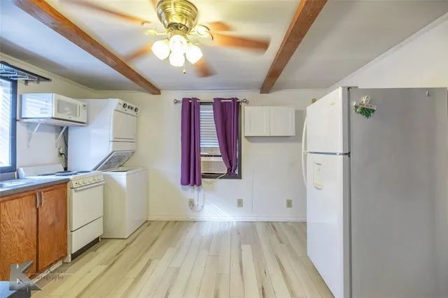 a kitchen with stainless steel appliances granite countertop a refrigerator a sink dishwasher a stove and white countertops with wooden floor