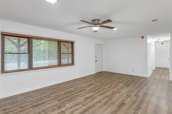 a view of empty room with wooden floor and fan